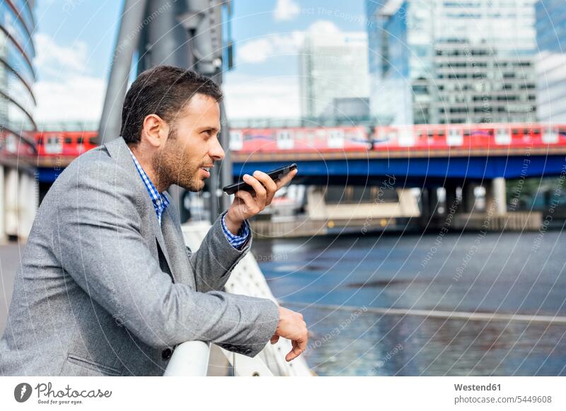 Businessman sending voice messages with his smartphone in the city on the phone call telephoning On The Telephone calling mobile phone mobiles mobile phones