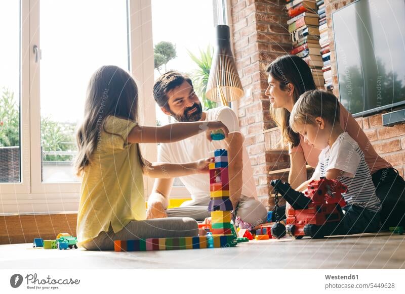 Family playing with building blocks on the floor together family families people persons human being humans human beings home at home fantasy mid adult women
