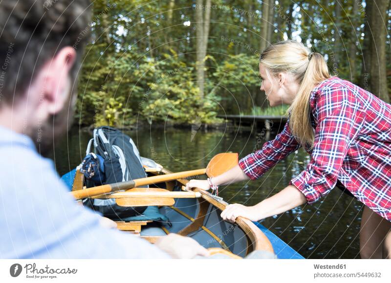 Young woman pulling canoe on a forest brook with man inside brooks rivulet couple twosomes partnership couples females women woods forests water waters