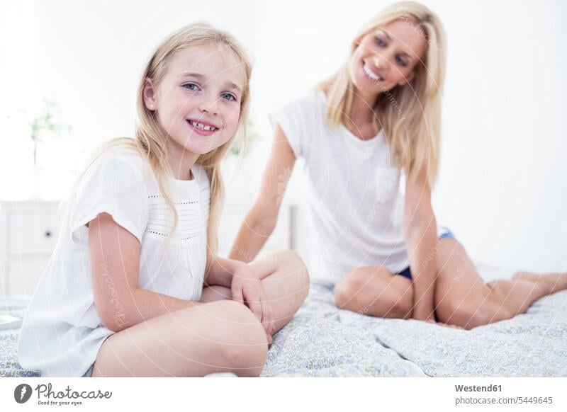 Portait of smiling girl sitting on bed with mother Seated smile daughter daughters beds mommy mothers ma mummy mama child children family families people