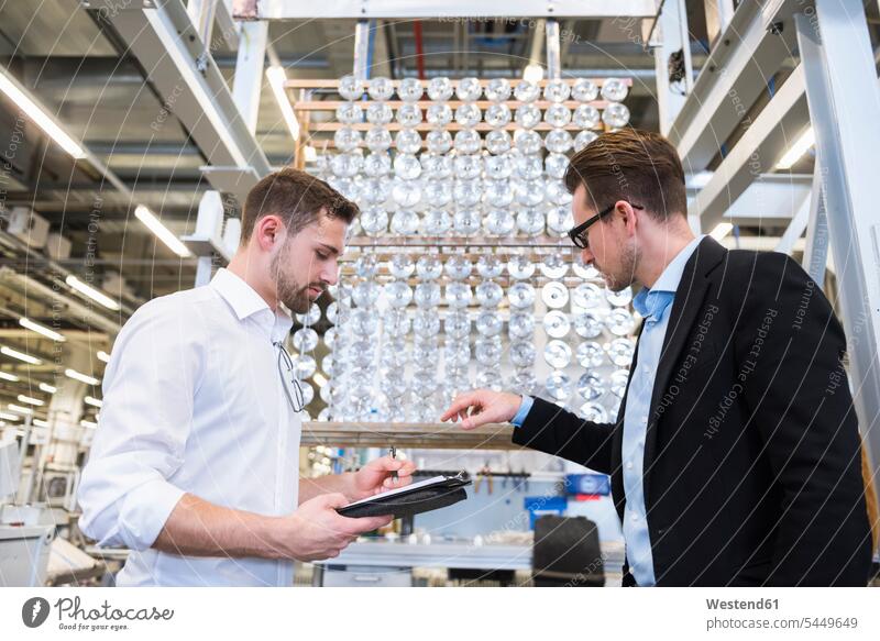 Two men in factory shop floor examining products man males talking speaking factories Adults grown-ups grownups adult people persons human being humans