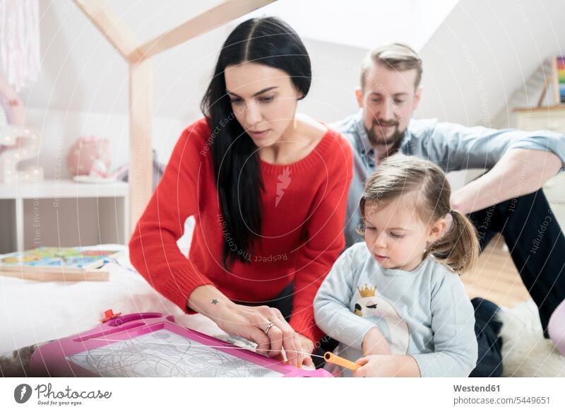 Parents playing with toddler daughter in nursery daughters children's room Kids Room child's room family families people persons human being humans human beings