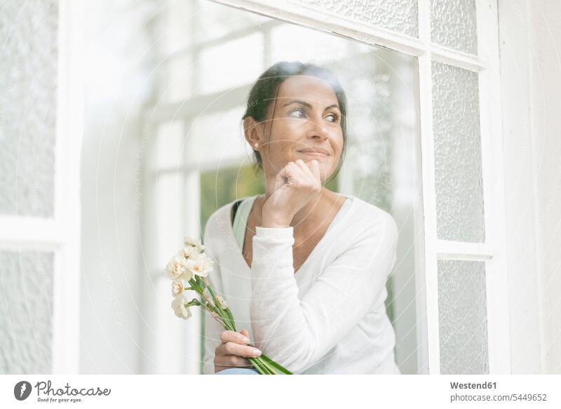 Smiling woman with flowers out of window smiling smile Flower Flowers females women windows looking view seeing viewing Adults grown-ups grownups adult people