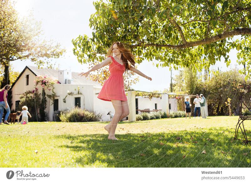 Girl wearing a red dress spinning around outside on the lawn playing garden gardens domestic garden girl females girls child children kid kids people persons