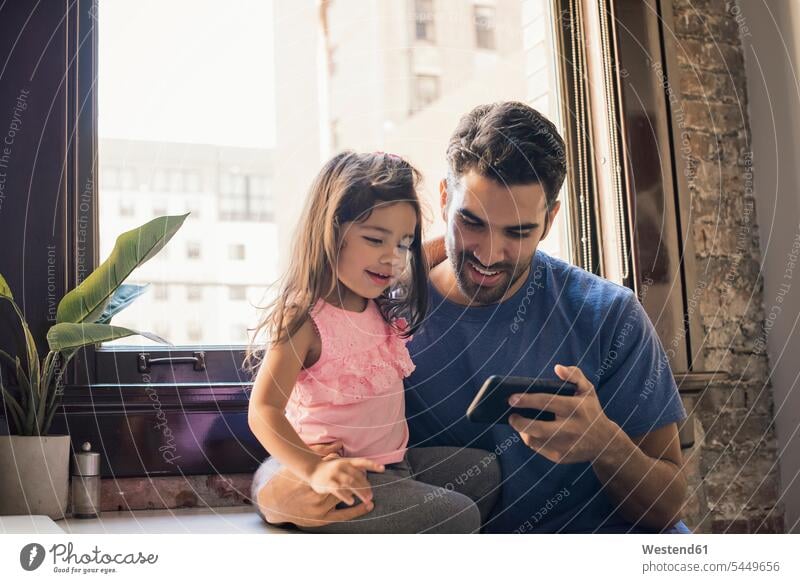 Father with daughter using smart phone in kitchen father pa fathers daddy dads papa Smartphone iPhone Smartphones daughters home at home parents family families