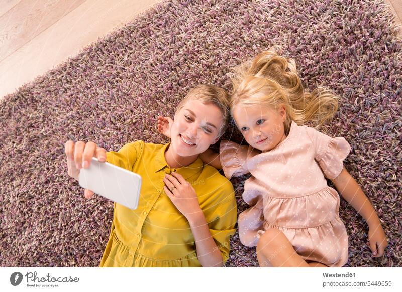 Smiling mother and daughter lying on carpet taking a selfie laying down lie lying down smiling smile Selfie Selfies mommy mothers ma mummy mama daughters