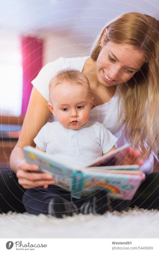 Mother and baby son looking at a picture book sons manchild manchildren mother mommy mothers mummy mama infants nurselings babies reading out read out family