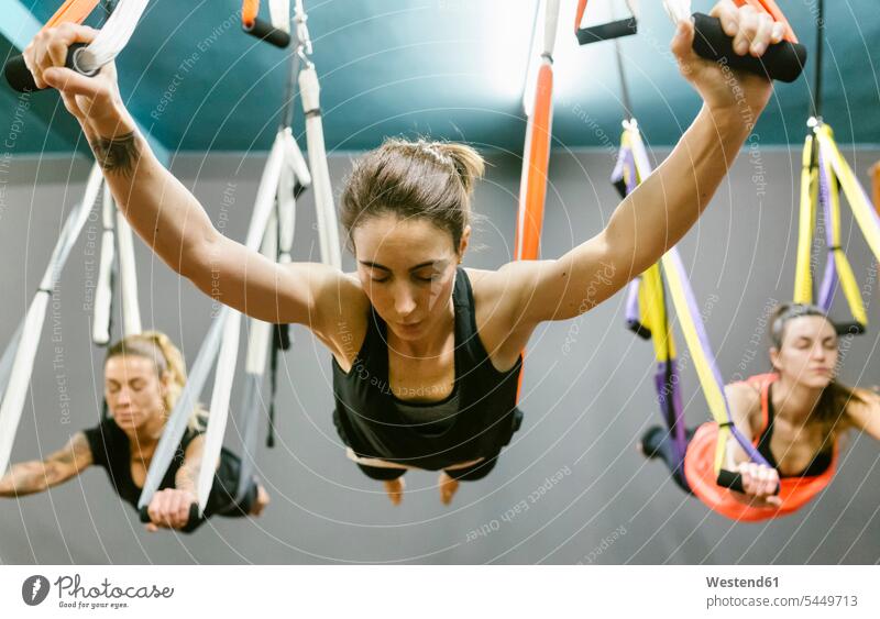 Group of women having a class of aerial yoga exercise exercises woman females exercising training practising mindfulness aware awareness self-care