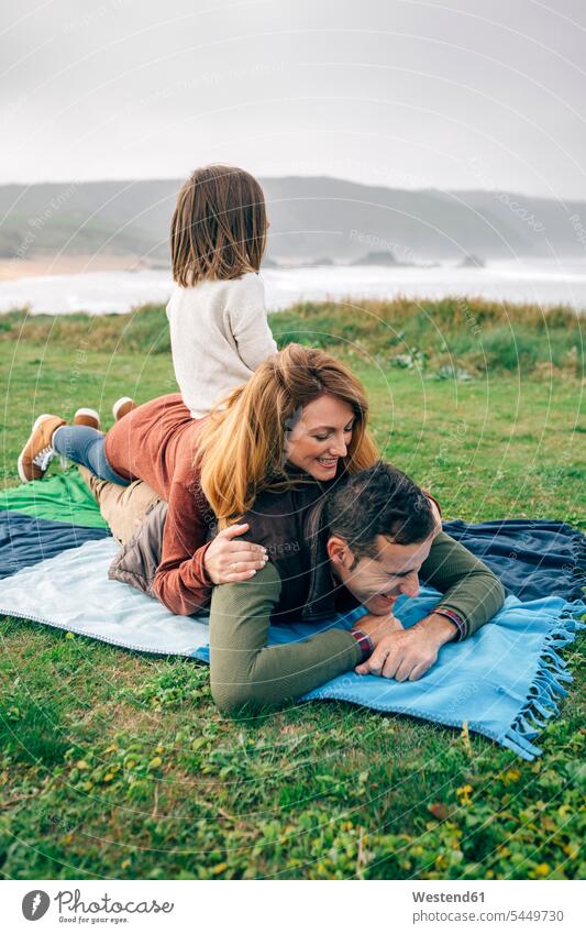 Happy family on blanket at the coast Blanket Blankets coastline shoreline happiness happy families people persons human being humans human beings Sea ocean