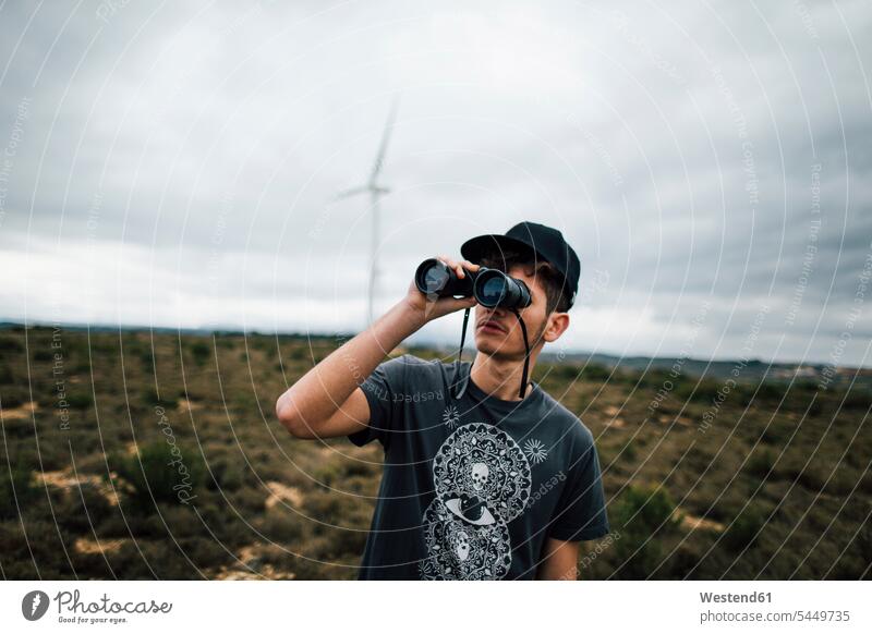 Spain, Lleida, young man looking through binoculars in rural landscape men males watching Adults grown-ups grownups adult people persons human being humans