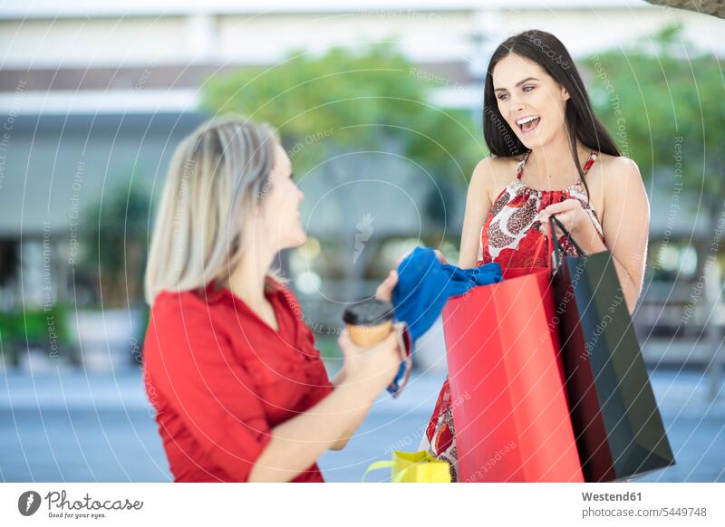 Two happy women with shopping bags female friends laughing Laughter happiness shopping-bag shopping-bags mate friendship positive Emotion Feeling Feelings