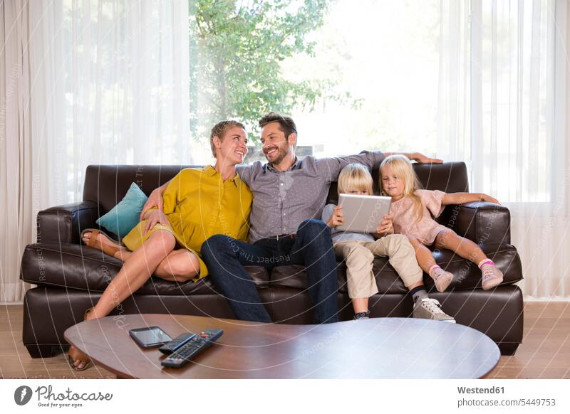 Family sitting on couch at home using tablet Seated family families use digitizer Tablet Computer Tablet PC Tablet Computers iPad Digital Tablet digital tablets