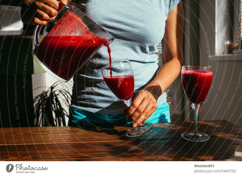Woman pouring fresh squeezed juice into glasses, partial view Juice Juices preparing Food Preparation preparing food Drink beverages Drinks Beverage