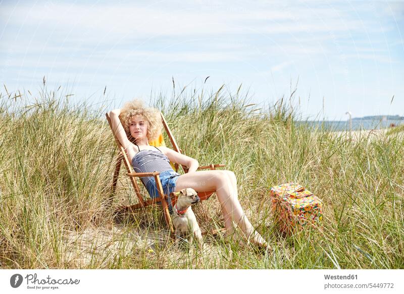 Portrait of young woman sitting on beach chair in the dunes watching something meadow meadows beachchair beach chairs beachchairs females women Adults grown-ups