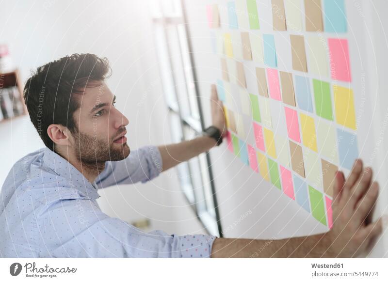 Young businessman working in office with sticky notes on wall strategy strategic Strategies Brainstorming writing write Adhesive Note Adhesive Notes