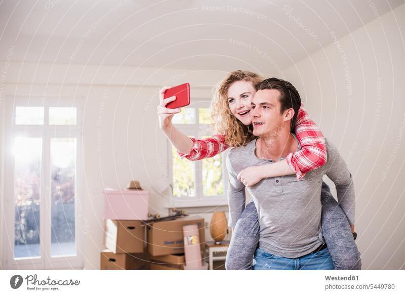 Happy young couple in new home taking a selfie flat flats apartment apartments mobile phone mobiles mobile phones Cellphone cell phone cell phones Fun