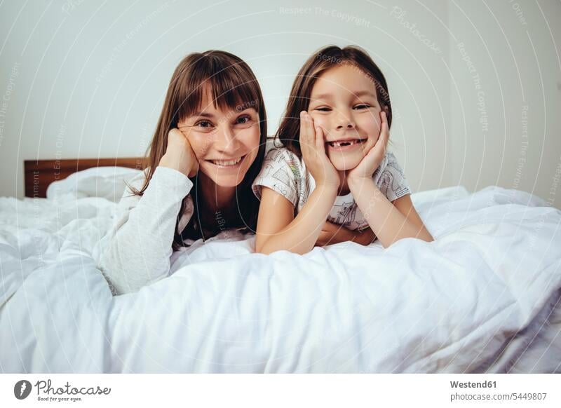 Portrait of happy mother and daughter in bed portrait portraits mommy mothers ma mummy mama family families daughters smiling smile beds parents people persons