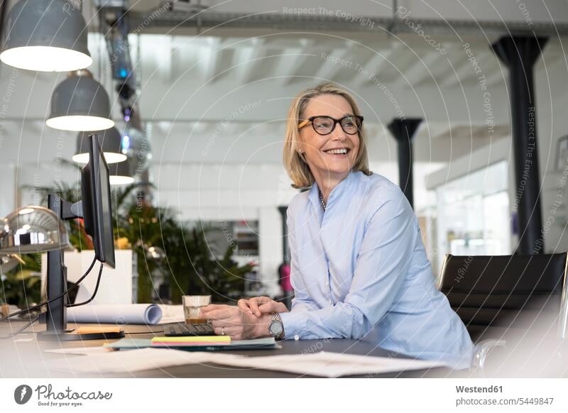 Mature businesswoman working in office, smiling At Work desk desks happiness happy sitting Seated businesswomen business woman business women fit offices