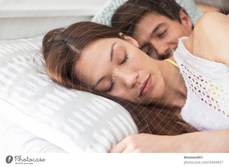 Young couple sleeping in bed asleep lying laying down lie lying down beds woman females women Adults grown-ups grownups adult people persons human being humans