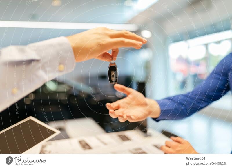 Salesperson handing over car keys to customer selling clientele clients customers buying automobile Auto cars motorcars Automobiles people persons human being
