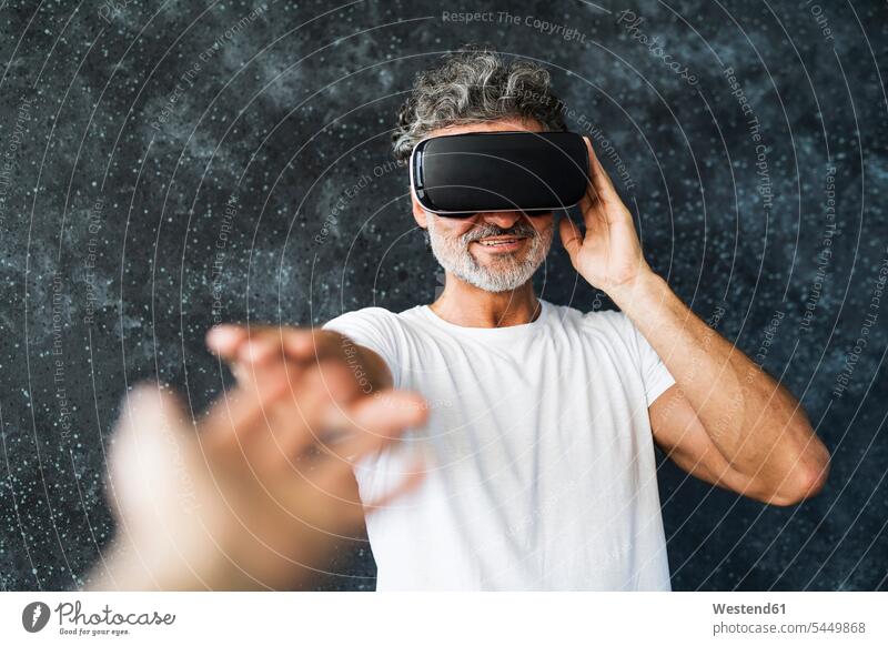 Mature man wearing VR glasses reaching out with hands t-shirt tee-shirt T- Shirt t-shirts digitization digitazing digitalisation digitalization interactive