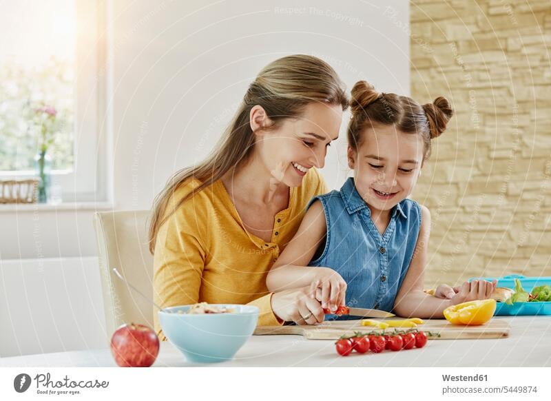 Happy mother with daughter at home cutting vegetables Vegetable Vegetables smiling smile happiness happy daughters mommy mothers ma mummy mama Food foods