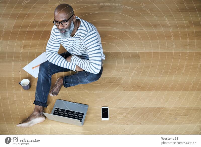 Mature man sitting on floor, working on laptop Laptop Computers laptops notebook Smartphone iPhone Smartphones men males home at home barefoot naked feet
