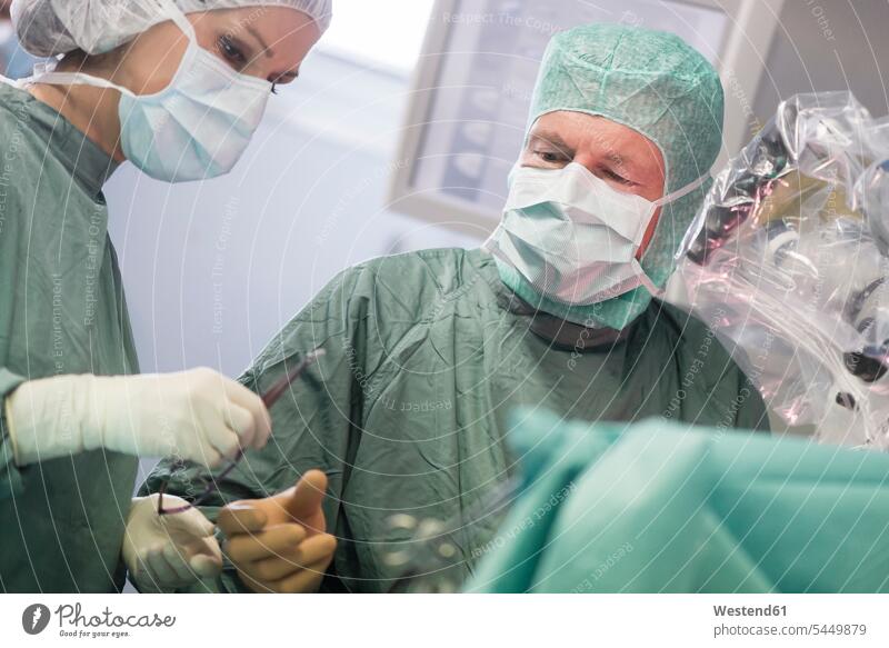 Operating room nurse handing over instrument during an operation surgery surgeries operating operating room nurse doctor physicians doctors treatment