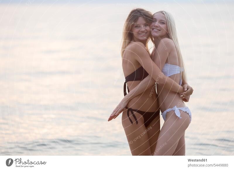 Two young women hugging at the sea Fun having fun funny ocean female friends happiness happy couple twosomes partnership couples water waters body of water mate