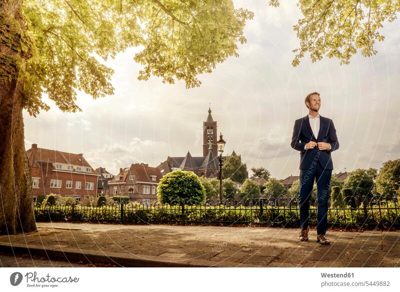 Netherlands, Venlo, businessman standing on pavement city town cities towns Businessman Business man Businessmen Business men outdoors outdoor shots