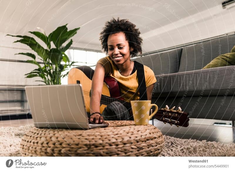 Smiling young woman at home with guitar and laptop smiling smile guitars females women Laptop Computers laptops notebook stringed instrument