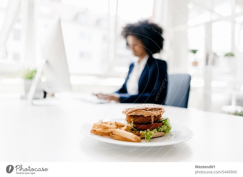 Young businesswoman working with hamburger on her desk Burger young At Work businesswomen business woman business women Lunch fast food fastfood Food foods