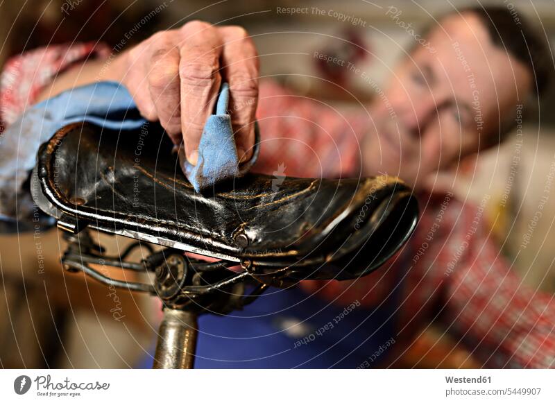 Senior man cleaning bicycle seat in his workshop, close-up senior men senior man elder man elder men senior citizen hand human hand hands human hands