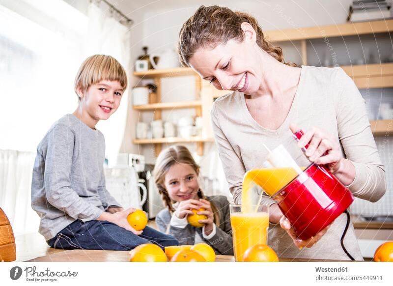 Woman pouring freshly squeezed orange juice into glass for children kitchen domestic kitchen kitchens Juice Juices Drink beverages Drinks Beverage