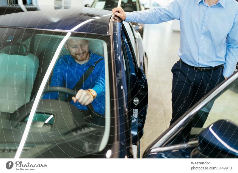 Salesman advising customer in car dealership counseling advise selling clientele clients customers choosing select choose selecting automobile Auto cars