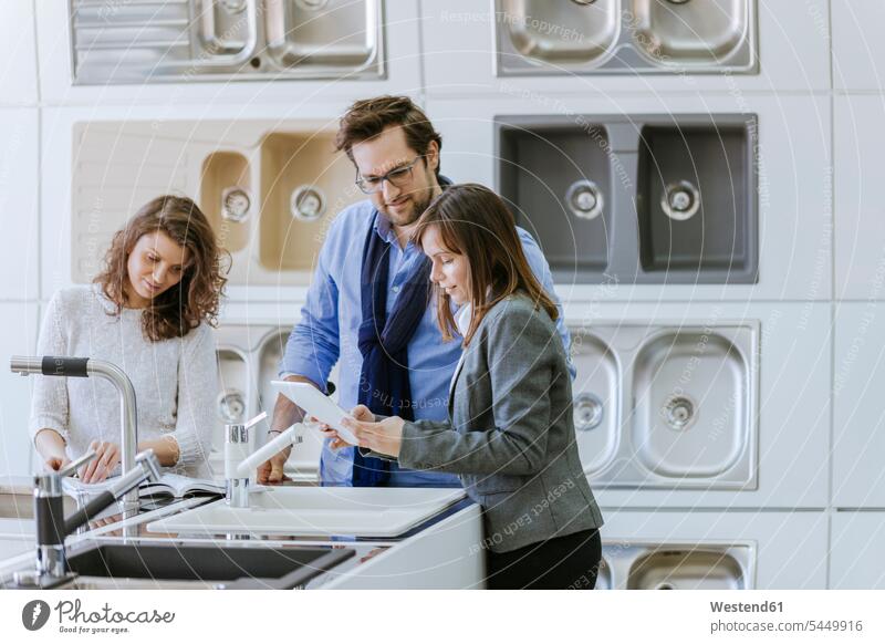 Customers consulting saleswoman in shop for kitchen sinks Saleswoman saleswomen selling kitchen retailer kitchen retailers female customer buying clientele
