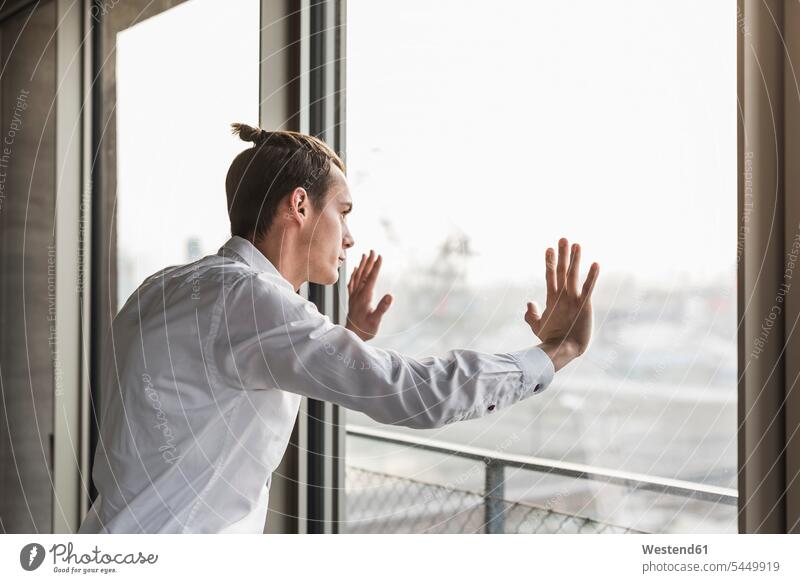Young businessman looking out of window windows Businessman Business man Businessmen Business men view seeing viewing business people businesspeople