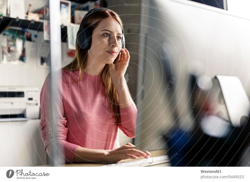 Portrait of young woman wearing headphones at desk at home desks headset portrait portraits females women Table Tables Adults grown-ups grownups adult people