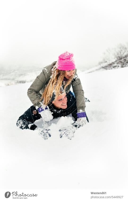 Young couple having fun in the snow playing laughing Laughter winter hibernal snowball fight snowball fights twosomes partnership couples positive Emotion