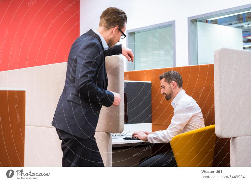 Two businessmen talking in office colleagues speaking private discussing discussion work meeting briefing offices office room office rooms conference workplace