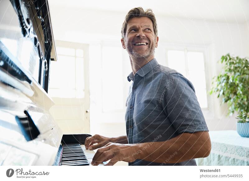 Mature man playing piano at home Fun having fun funny practicing practice practise exercise exercising practising cheerful gaiety Joyous glad Cheerfulness
