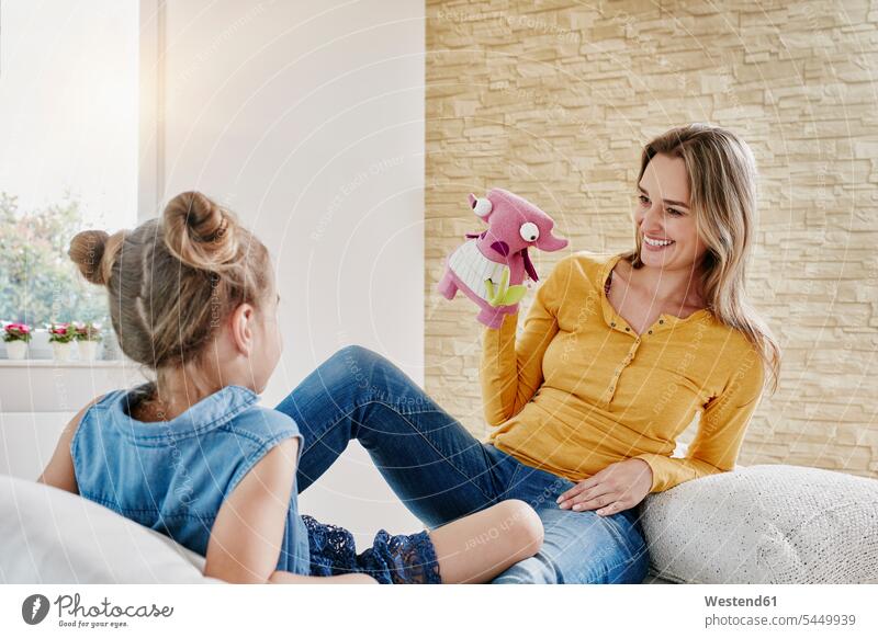 Happy mother and daughter playing with cuddly toy at home mommy mothers ma mummy mama looking eyeing soft toy soft toys daughters Fun having fun funny happiness