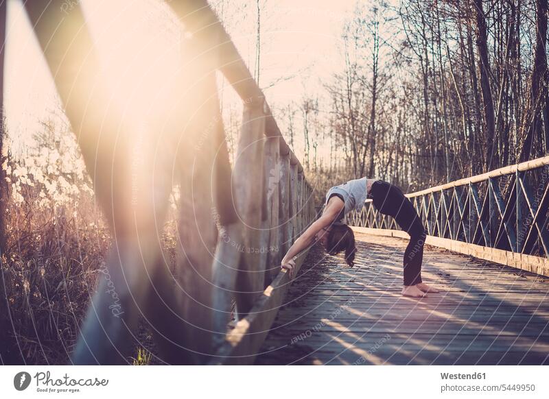 Woman doing wheel pose on a bridge yoga woman females women bridges nature natural world mindfulness aware awareness self-care relaxation exercise relaxed