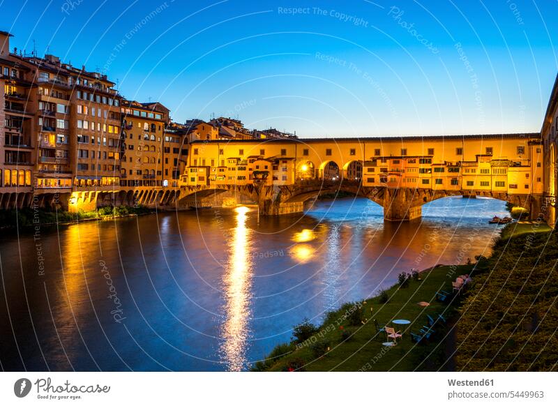 Italy, Tuscany, Florence, view to Arno River and lighted Ponte Vecchio at blue hour illuminated lit Illuminating historic historical ancient multi-family house