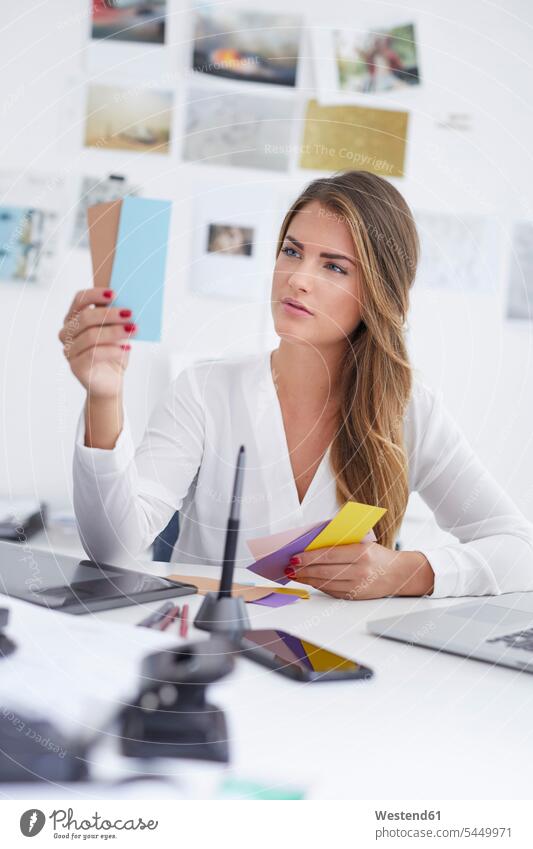 Young woman looking at notes at desk in office slip offices office room office rooms working At Work memo notice workplace work place place of work