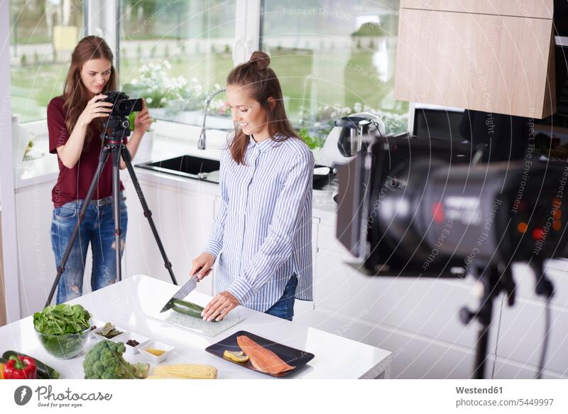 Woman recording her friend while chopping a courgette cook cameras smile human human being human beings humans person persons adult grown-up grown-ups grownup