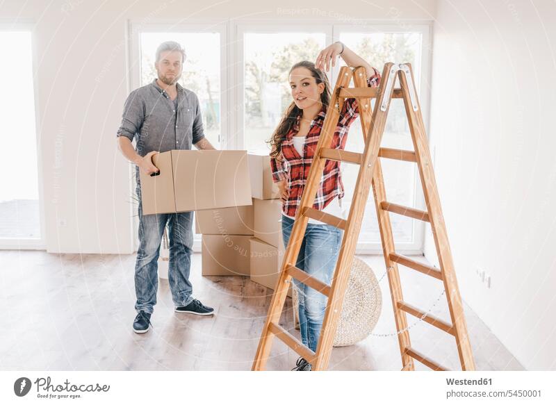 Couple moving house, carrying boxes in new home owner owners flat flats apartment apartments couple twosomes partnership couples property move Moving Home