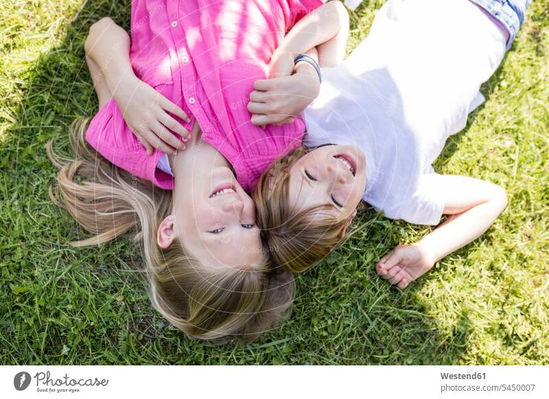 Two happy sisters lying in meadow laying down lie lying down happiness relaxed relaxation meadows garden gardens domestic garden girl females girls relaxing