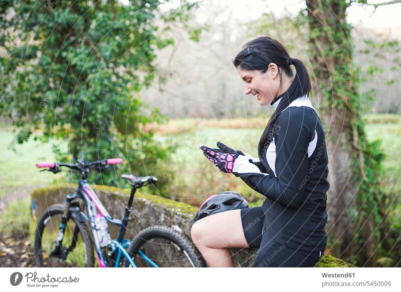 Happy woman with mountain bike checking her cell phone females women mountain biking MTB mountainbiking mobile phone mobiles mobile phones Cellphone cell phones