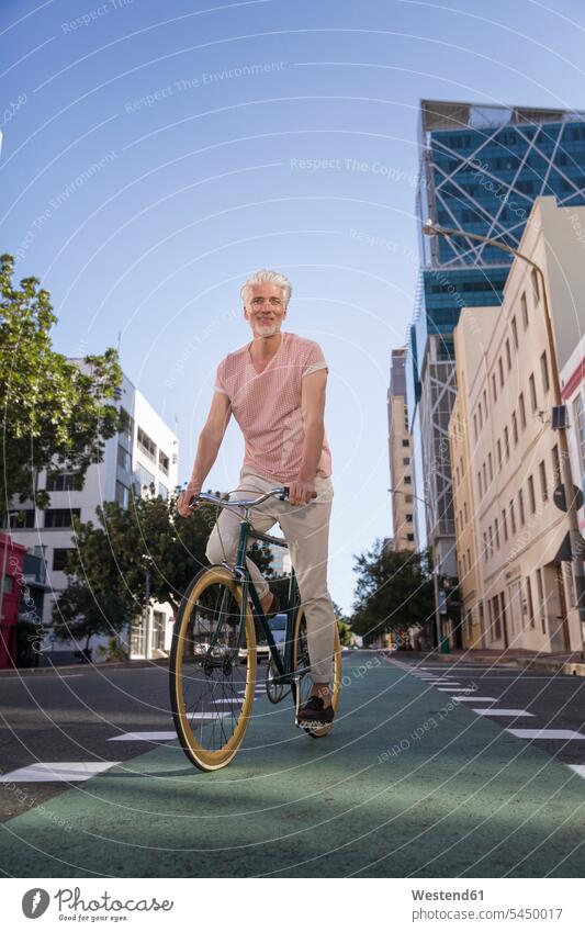 Mature man riding bicycle in the city smiling smile town cities towns bikes bicycles on the move on the way on the go on the road riding bike bike riding